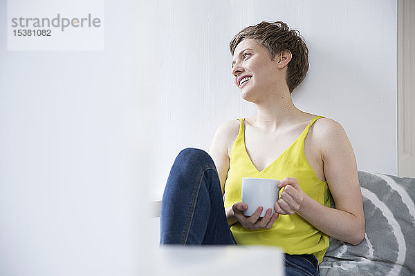 Lächelnde Frau mit Tasse Kaffee zu Hause
