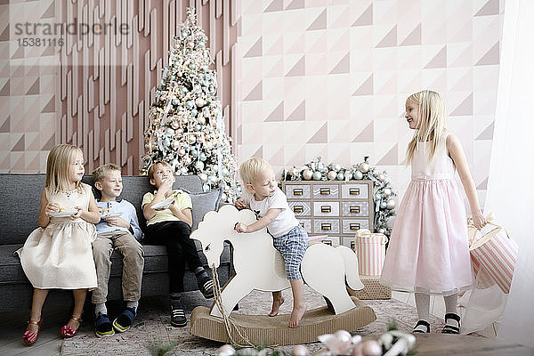 Fünf Kinder  die zur Weihnachtszeit im Wohnzimmer spielen und Kekse essen