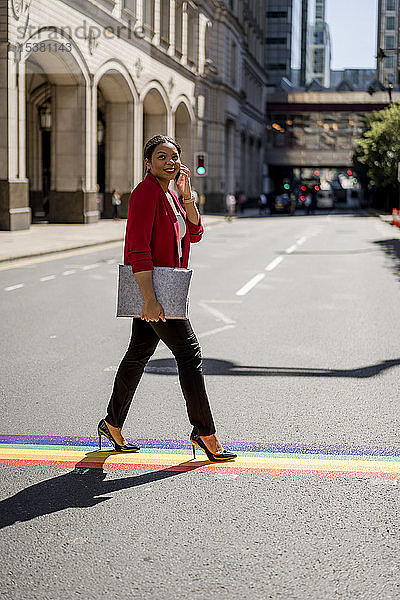 Porträt einer Geschäftsfrau am Telefon beim Überqueren der Straße auf LGBT-Streifen  London  UK