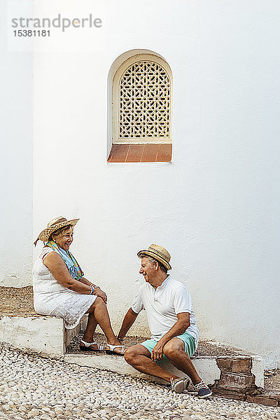 Glückliches älteres Touristenpaar  das auf Stufen in einem Dorf sitzt  El Roc de Sant Gaieta  Spanien