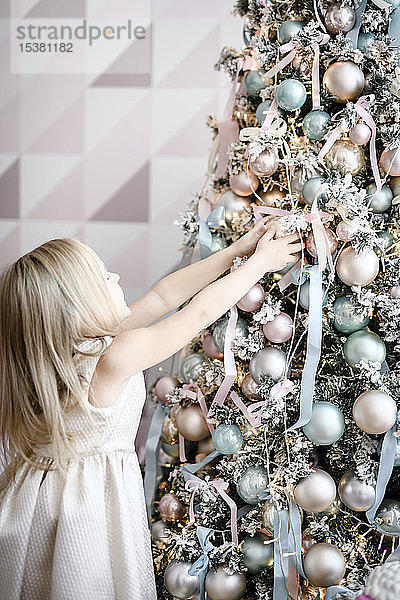 Kleines Mädchen beim Schmücken des Weihnachtsbaums