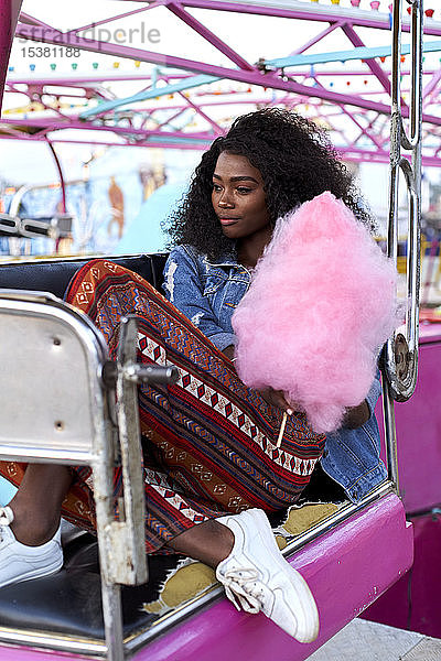 Porträt einer jungen Frau mit rosa Zuckerwatte auf dem Jahrmarkt