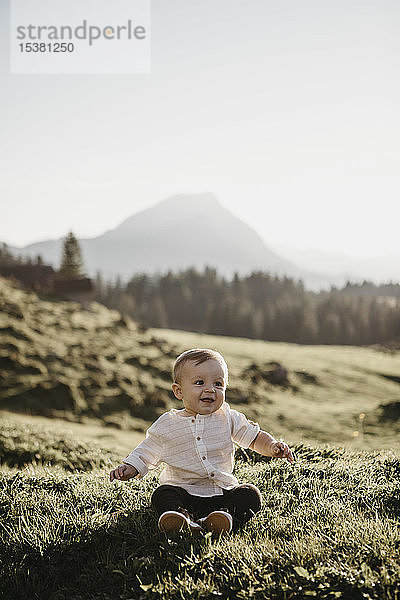 Glücklicher kleiner Junge sitzt auf einer Alpweide  Schwaegalp  Nesslau  Schweiz