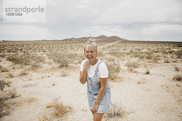 Porträt einer lachenden jungen Frau in einer Wüstenlandschaft  Joshua-Tree-Nationalpark  Kalifornien  USA