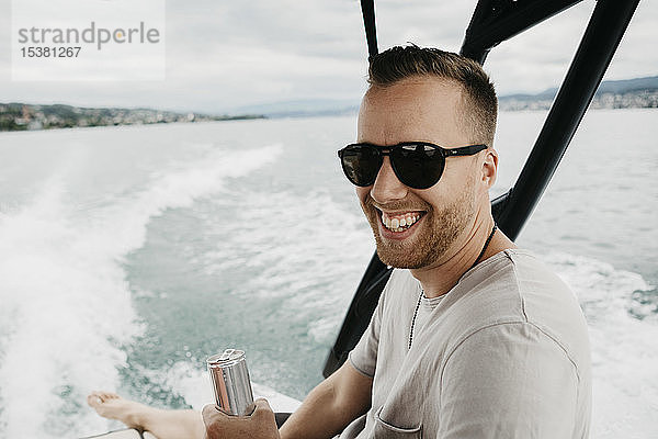 Glücklicher Mann mit Sonnenbrille bei einer Bootsfahrt auf einem See