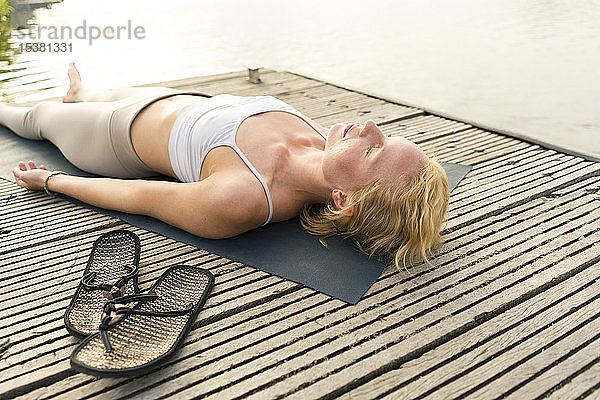 Junge Frau liegt auf einem Steg an einem See