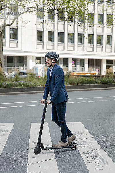 Junger Geschäftsmann fährt E-Scooter in der Stadt