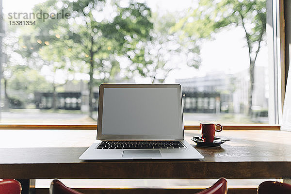 Laptop und Tasse Kaffee auf dem Tisch in einem Café