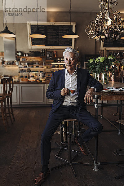 Porträt eines hochrangigen Geschäftsmannes  der in einem Café Espresso trinkt