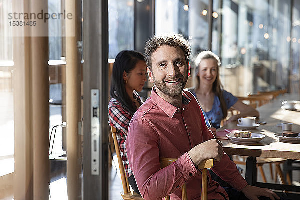 Porträt eines lächelnden Mannes mit Freunden in einem Cafe