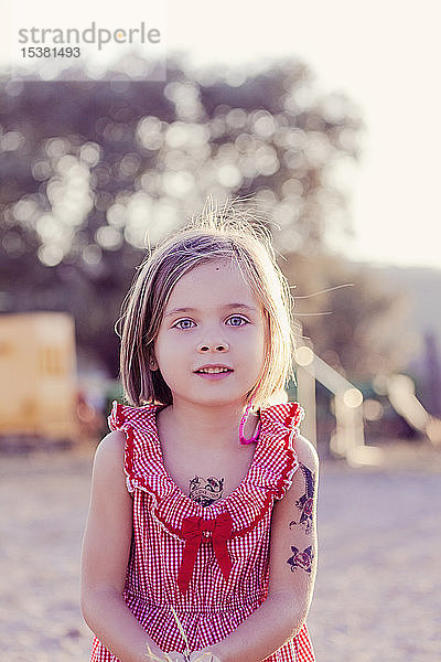Porträt eines kleinen Mädchens mit temporären Tätowierungen bei Sonnenuntergang