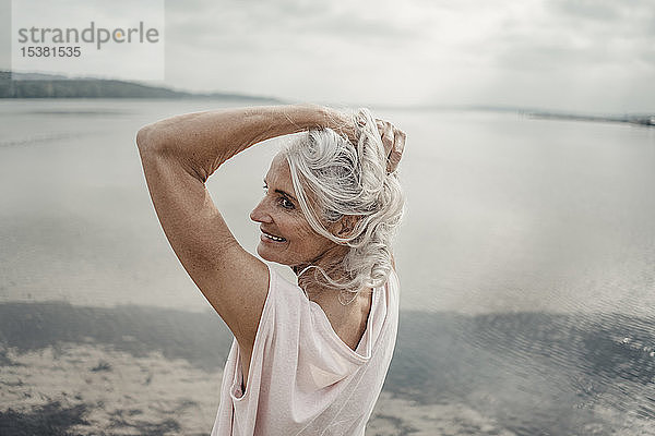Weißhaarige ältere Frau posiert am Meer