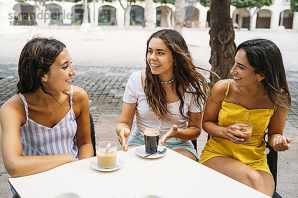 Drei glückliche Freundinnen in einem Café in der Stadt