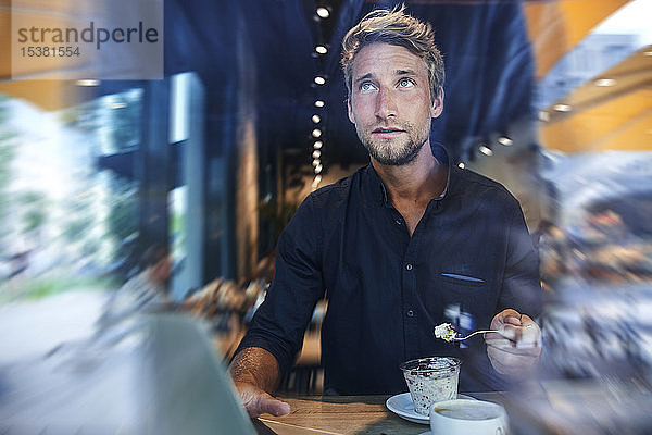Junger Geschäftsmann in einem Cafe beim Müsliessen