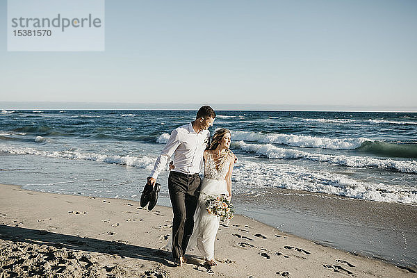 Braut und Bräutigam beim Spaziergang am Strand
