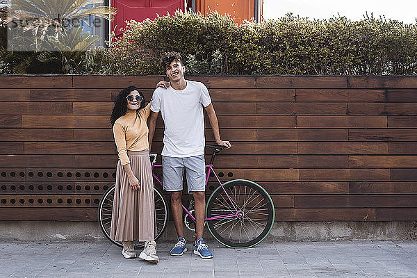 Glückliches Paar mit Fahrrad  an der Wand stehend