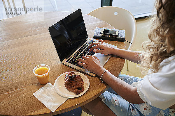 Junge Frau in einem Café mit Laptop beim Frühstück