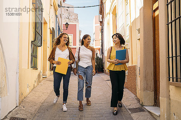 Drei glückliche Freundinnen laufen in der Stadt herum