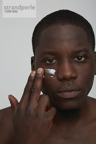Porträt eines Afrikaners  der Gesichtscreme aufträgt