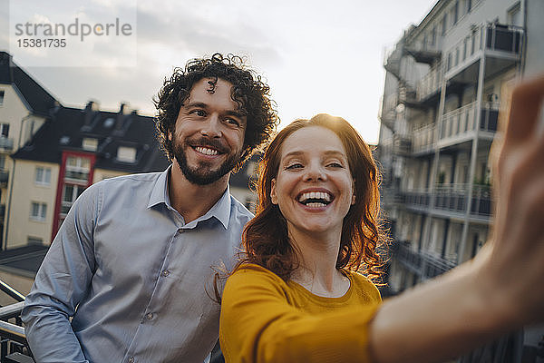 Zwei glückliche Kollegen auf der Dachterrasse beim Selfie