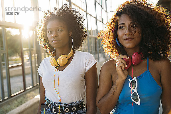 Porträt von zwei jungen Frauen mit Kopfhörern bei Sonnenuntergang