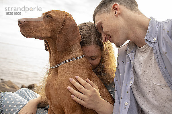 Junges Paar mit Hund am Strand