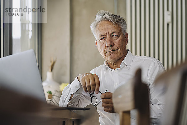 Porträt eines hochrangigen Geschäftsmannes mit Laptop in einem Cafe