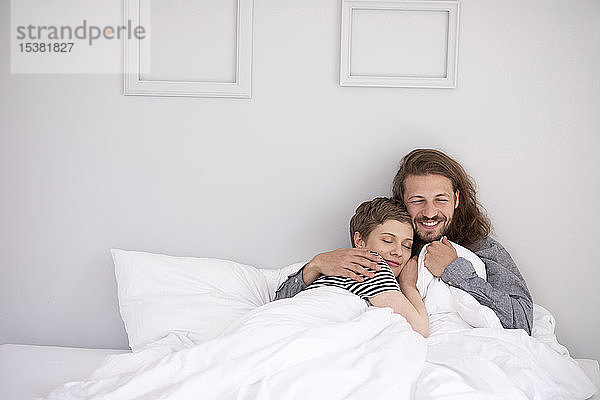 Glückliches junges Paar kuschelt zu Hause im Bett