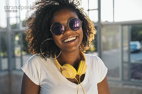 Porträt einer glücklichen jungen Frau mit Kopfhörer und Sonnenbrille