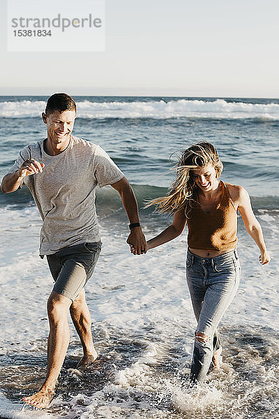 Glückliches junges Paar läuft am Meeresufer