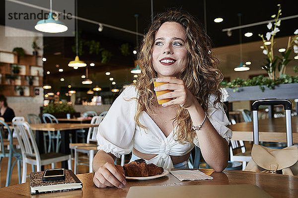Lächelnde junge Frau in einem Café beim Frühstück