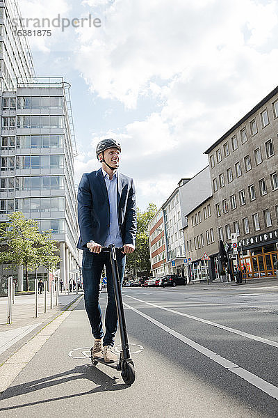 Junger Geschäftsmann auf dem E-Scooter auf dem Fahrradweg in der Stadt