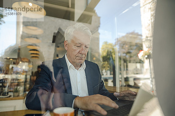 Leitender Geschäftsmann benutzt Laptop in einem Café