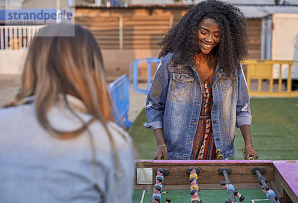 Porträt einer glücklichen jungen Frau  die mit ihrem Freund Tischfussball spielt