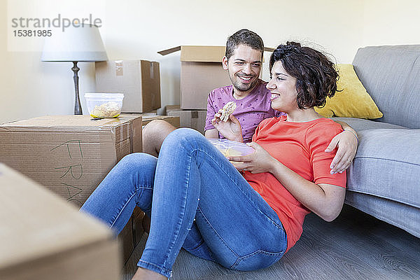 Glückliches Paar zieht in ein neues Zuhause ein  macht eine Pause und isst zu Mittag