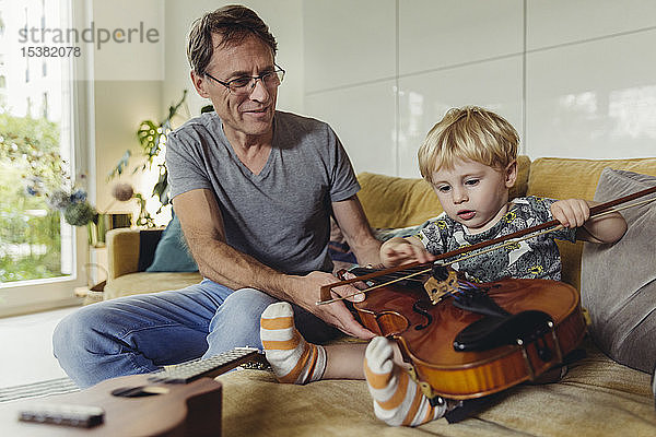 Porträt eines Kleinkindes beim Geigentest  während sein Vater zusieht
