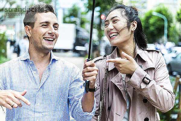 Glückliches Paar mit Regenschirm amüsiert sich in Ginza  Tokio  Japan