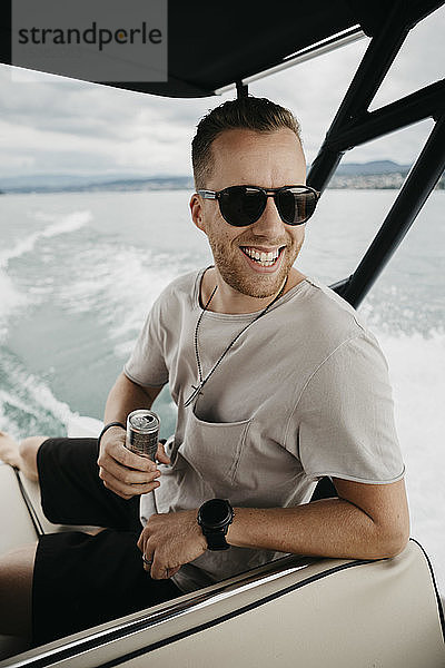 Glücklicher Mann mit Sonnenbrille bei einer Bootsfahrt auf einem See