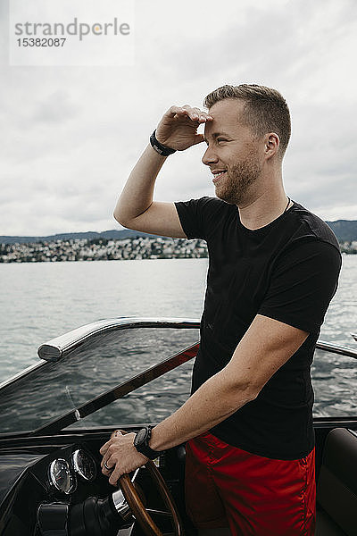 Lächelnder Mann steuert Boot auf einem See