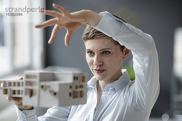 Selbstbewusste Geschäftsfrau mit Architekturmodell im Amt