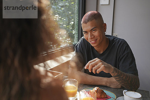 Porträt eines jungen Mannes  der mit seiner Freundin in einem Café frühstückt