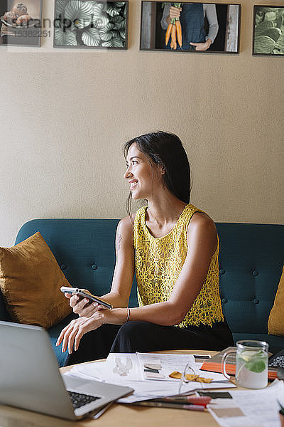 Lächelnder Modedesigner sitzt auf dem Sofa und macht eine Pause