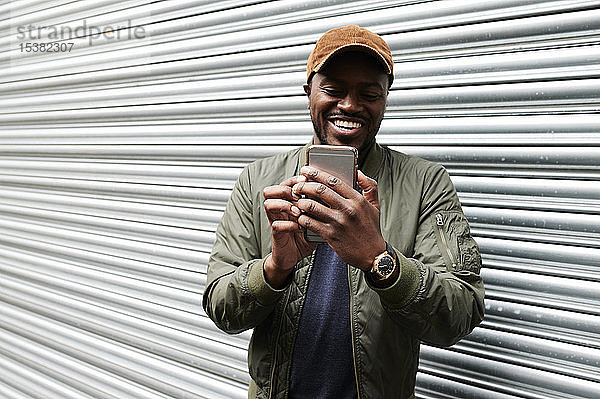 Porträt eines lachenden Mannes  der sich mit einem Smartphone selbstständig macht