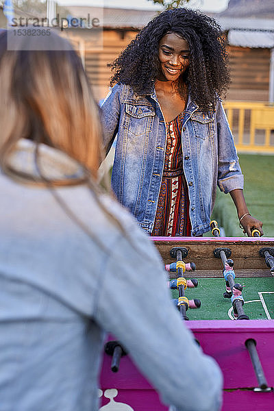 Porträt einer jungen Frau  die mit ihrem Freund Tischfussball spielt