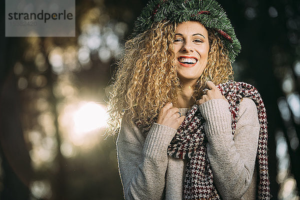 Porträt einer lachenden jungen Frau mit Weihnachtskranz auf dem Kopf