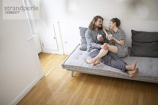 Glückliches junges Paar im Pyjama auf der Schlafcouch zu Hause
