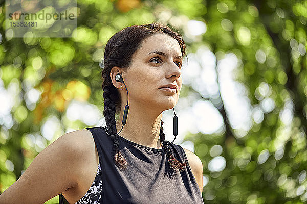Porträt einer sportlichen jungen Frau mit Kopfhörern im Wald
