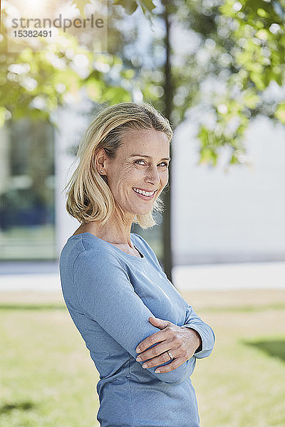 Porträt einer lächelnden blonden Frau in einem Park