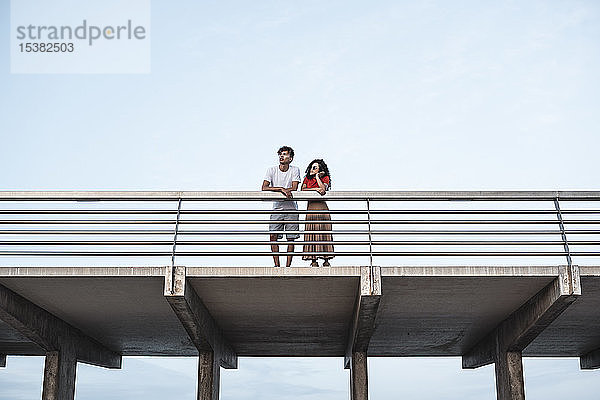 Junges Paar steht auf der Brücke und schaut auf die Aussicht