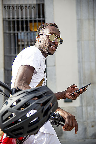 Junger Mann auf seinem Fahrrad mit seinem Smartphone